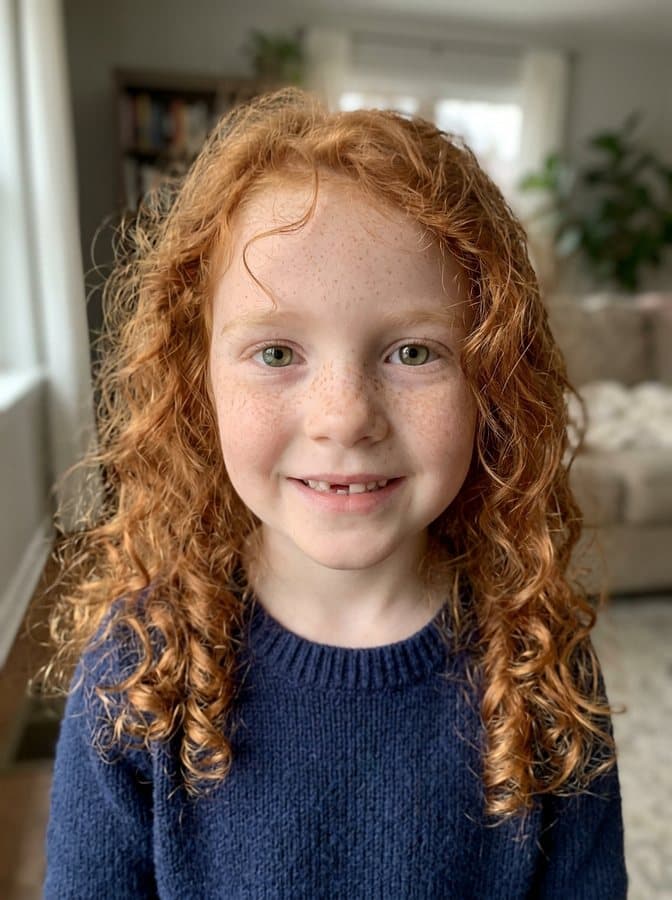 Photo of Nora, an invented girl with red curls, freckles and a missing front tooth, made with AI